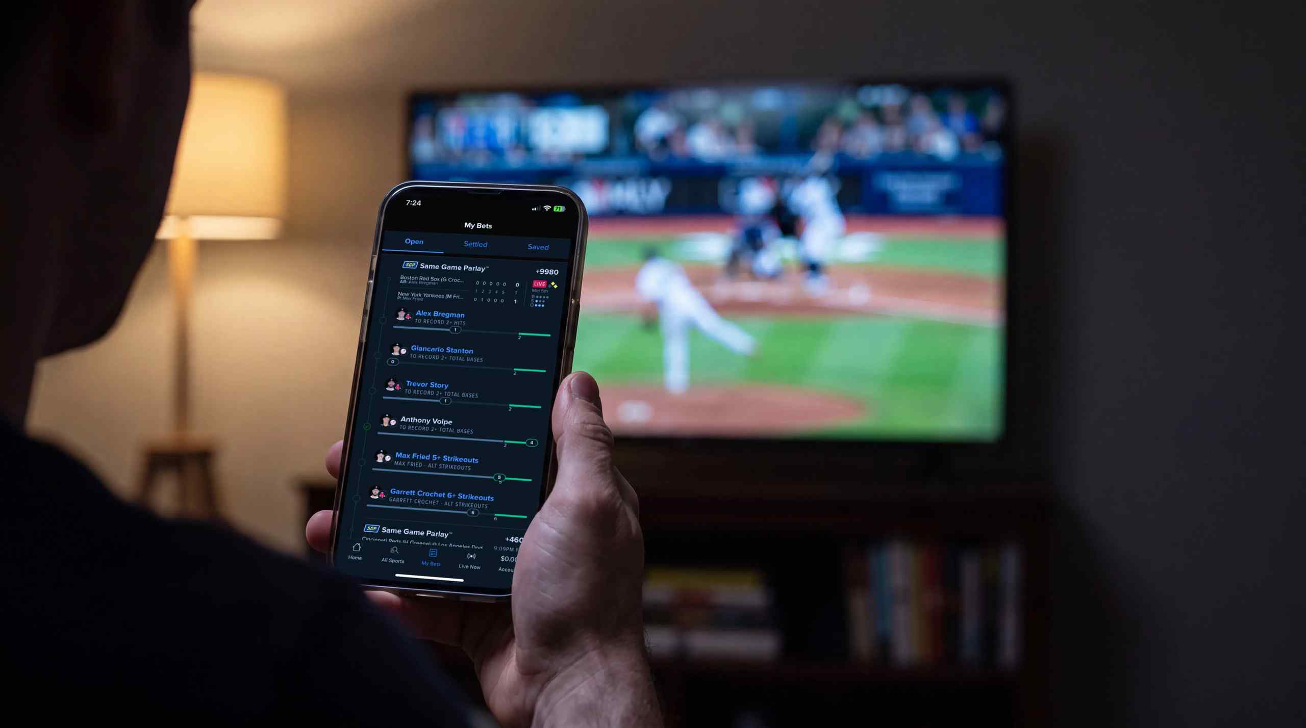 A man checking what bets are available on his phone with an MLB game in the background.